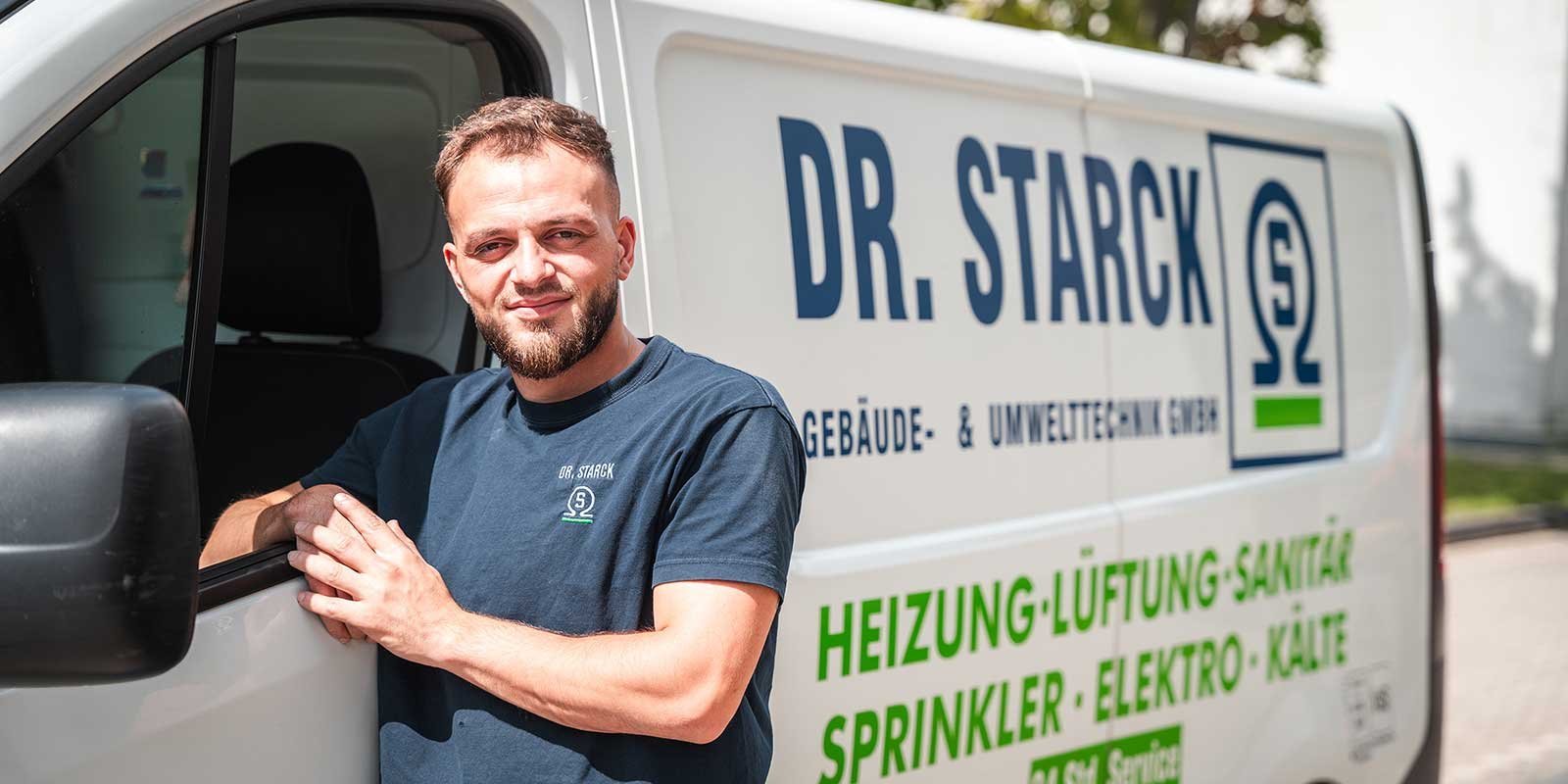 Ein junger Mann mit Bart steht lächelnd an einem Lieferwagen, der mit dem Logo von Dr. Starck beschriftet ist.